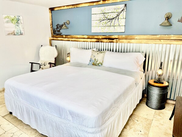A bed with a white bedspread, a wooden headboard, and a nightstand with a lamp.