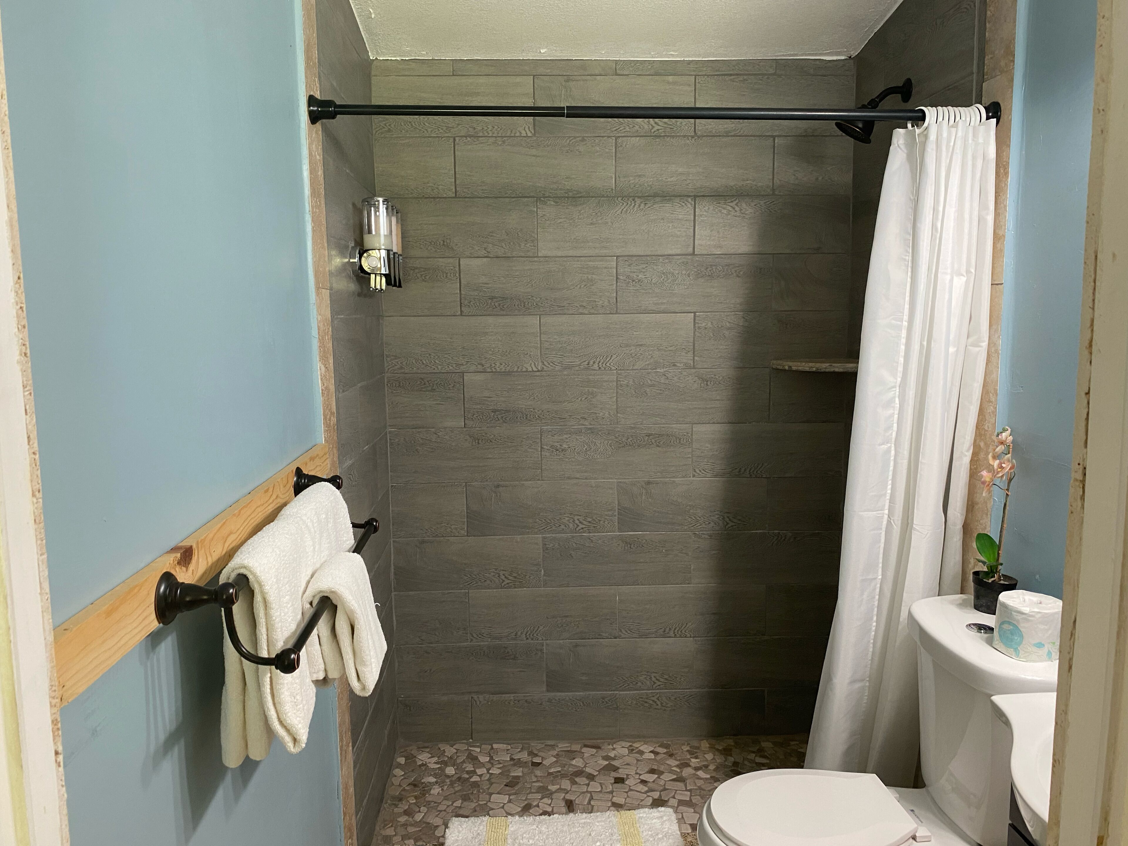 A bathroom with a shower, toilet, and a towel rack.