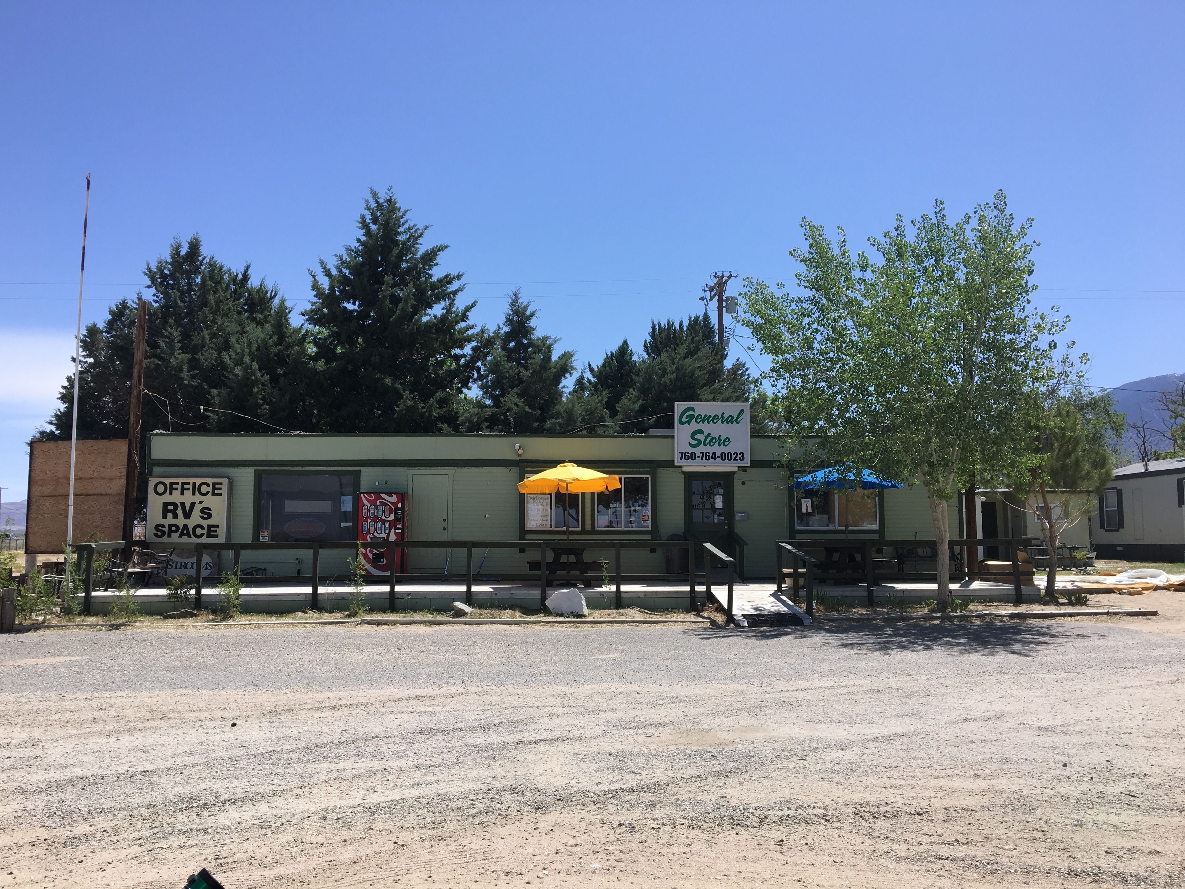 A small general store with a signboard, an office labeled 'RV's Space', and a yellow umbrella.