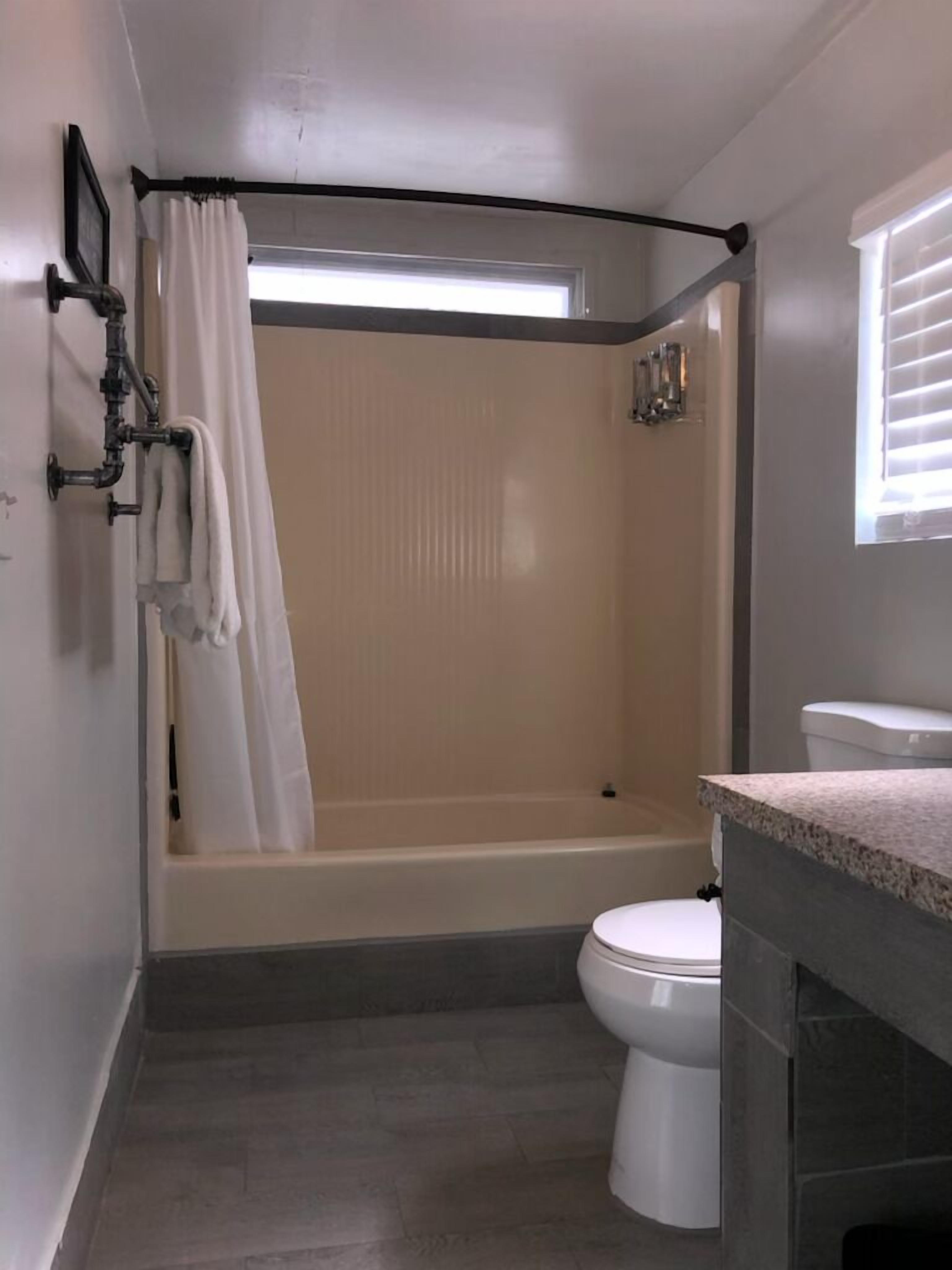 A bathroom with a bathtub, toilet, and a shower curtain.