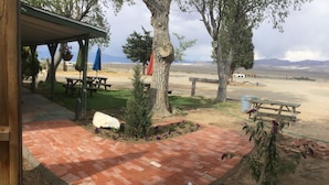 Un espace extérieur abrité avec des tables de pique-nique et une terrasse en briques.