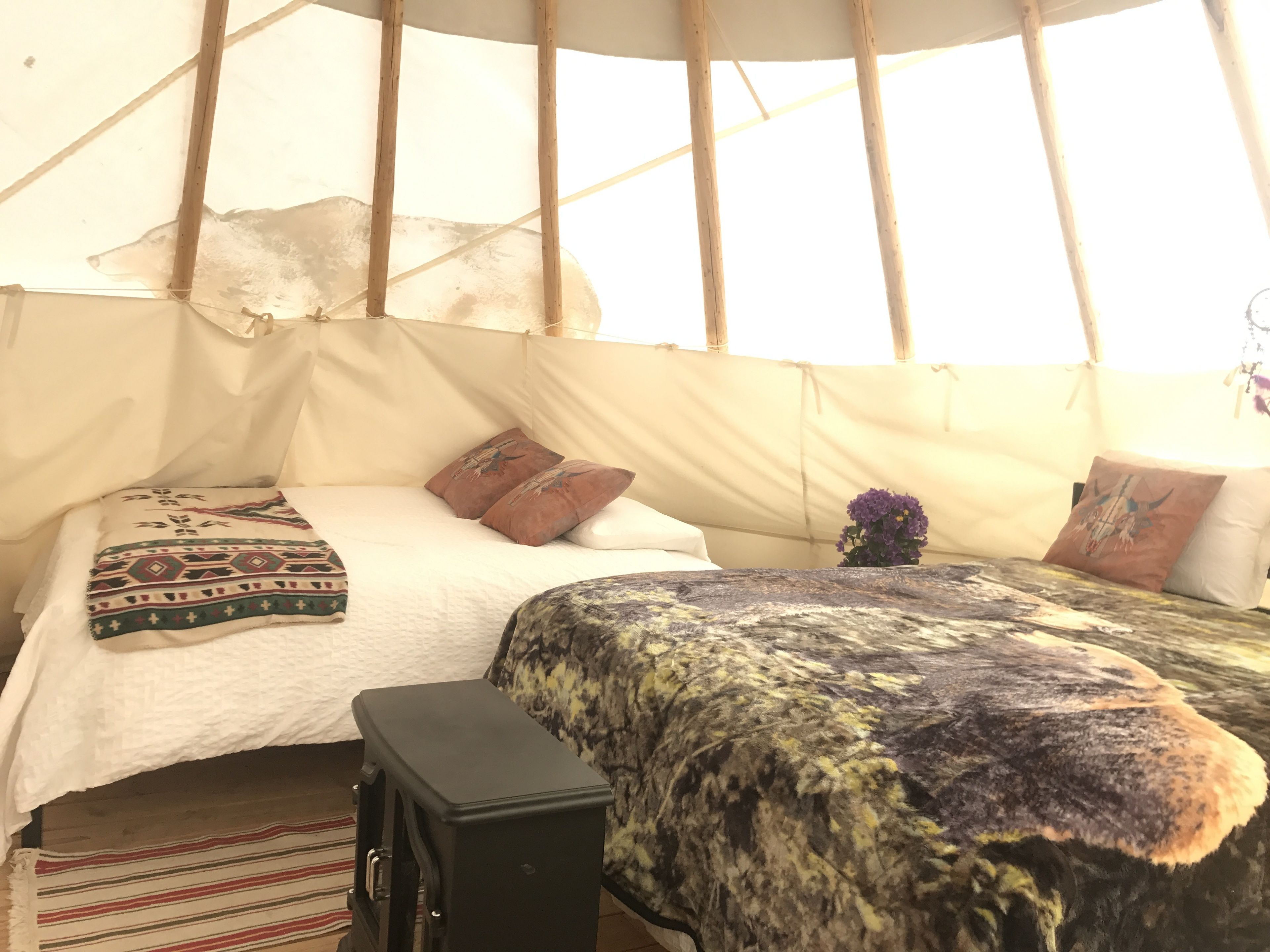 A cozy interior with a bed, pillows, a small cabinet, and a window.