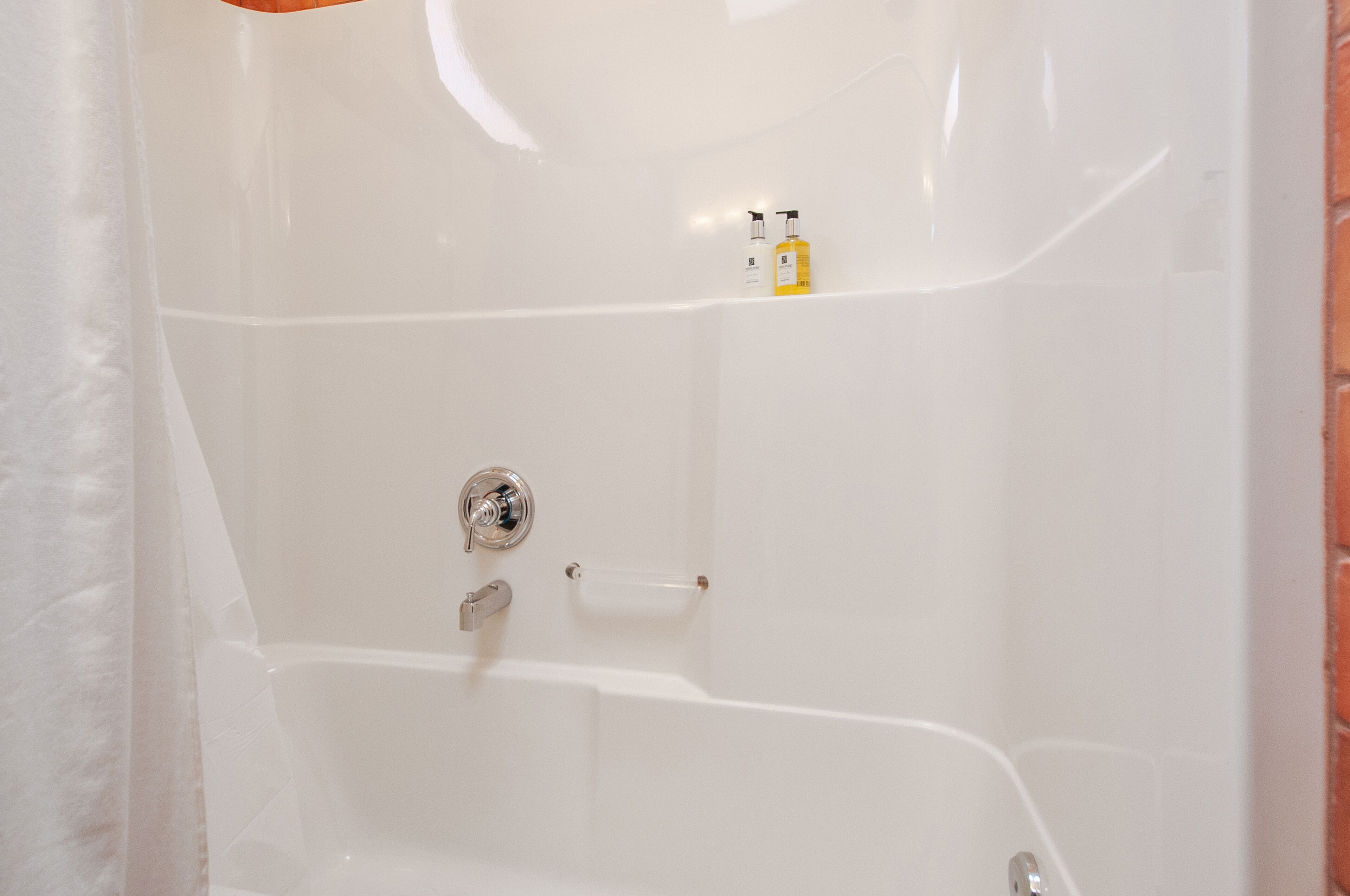 Une baignoire blanche avec un robinet chromé et un distributeur de savon.