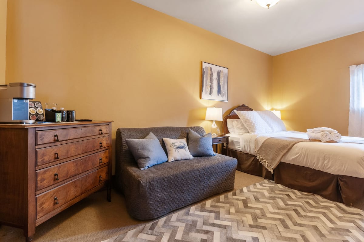 Una habitación de hotel con cama, sofá, cómoda y lámpara.