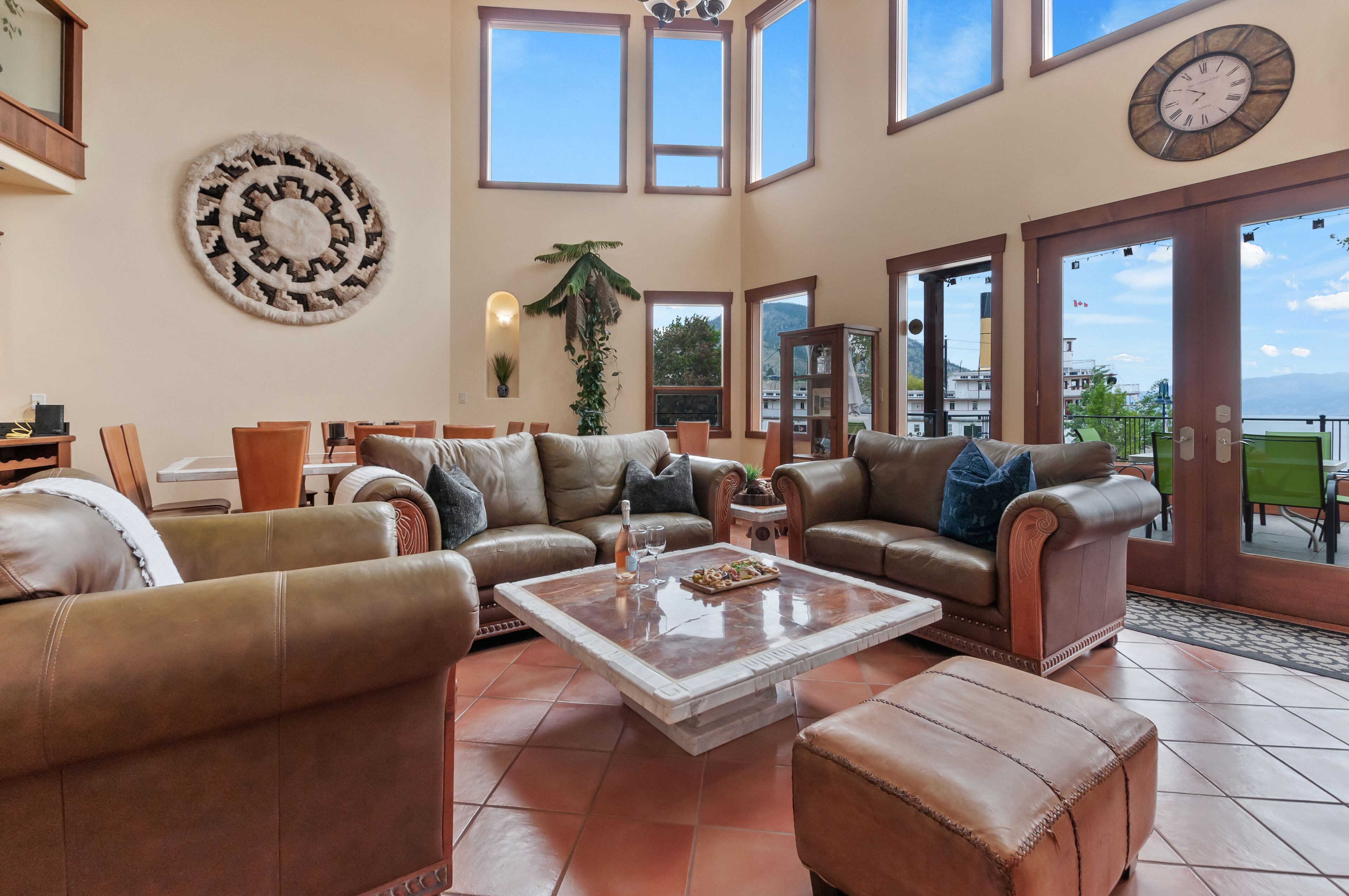 A spacious living room with leather sofas, a coffee table, and a large window offering a view of the outdoors.