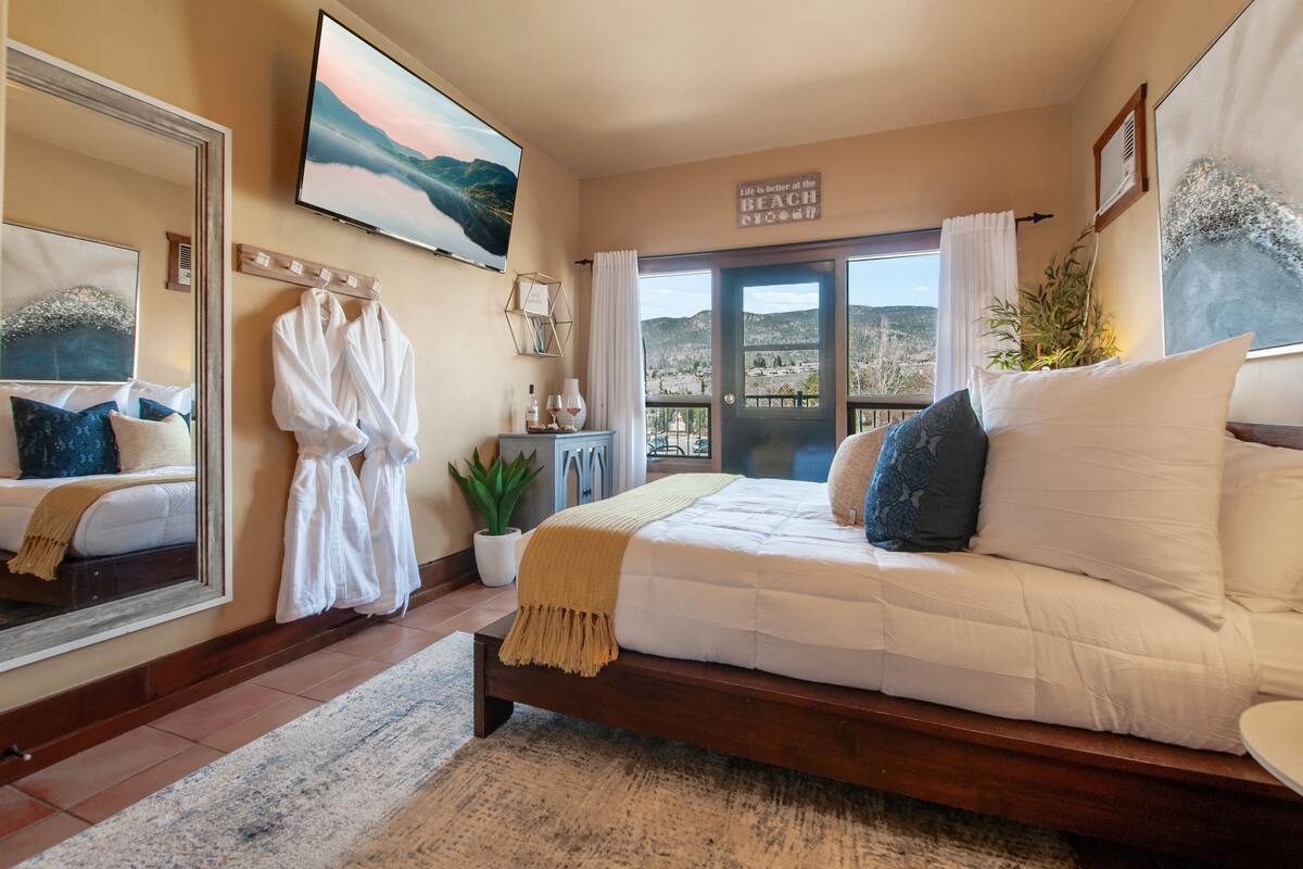 Un dormitorio con una cama grande, un espejo, un televisor, una ventana con vistas y un cartel en la pared.