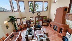 A spacious living area with a fireplace, multiple seating options, and large windows offering views of the outdoors. - Casa Grande Inn (Penticton)