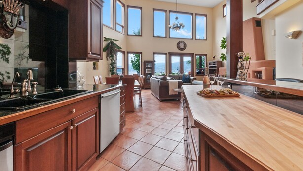A spacious kitchen with a large island, wooden cabinets, and a view of the outdoors. - Casa Grande Inn (Penticton)