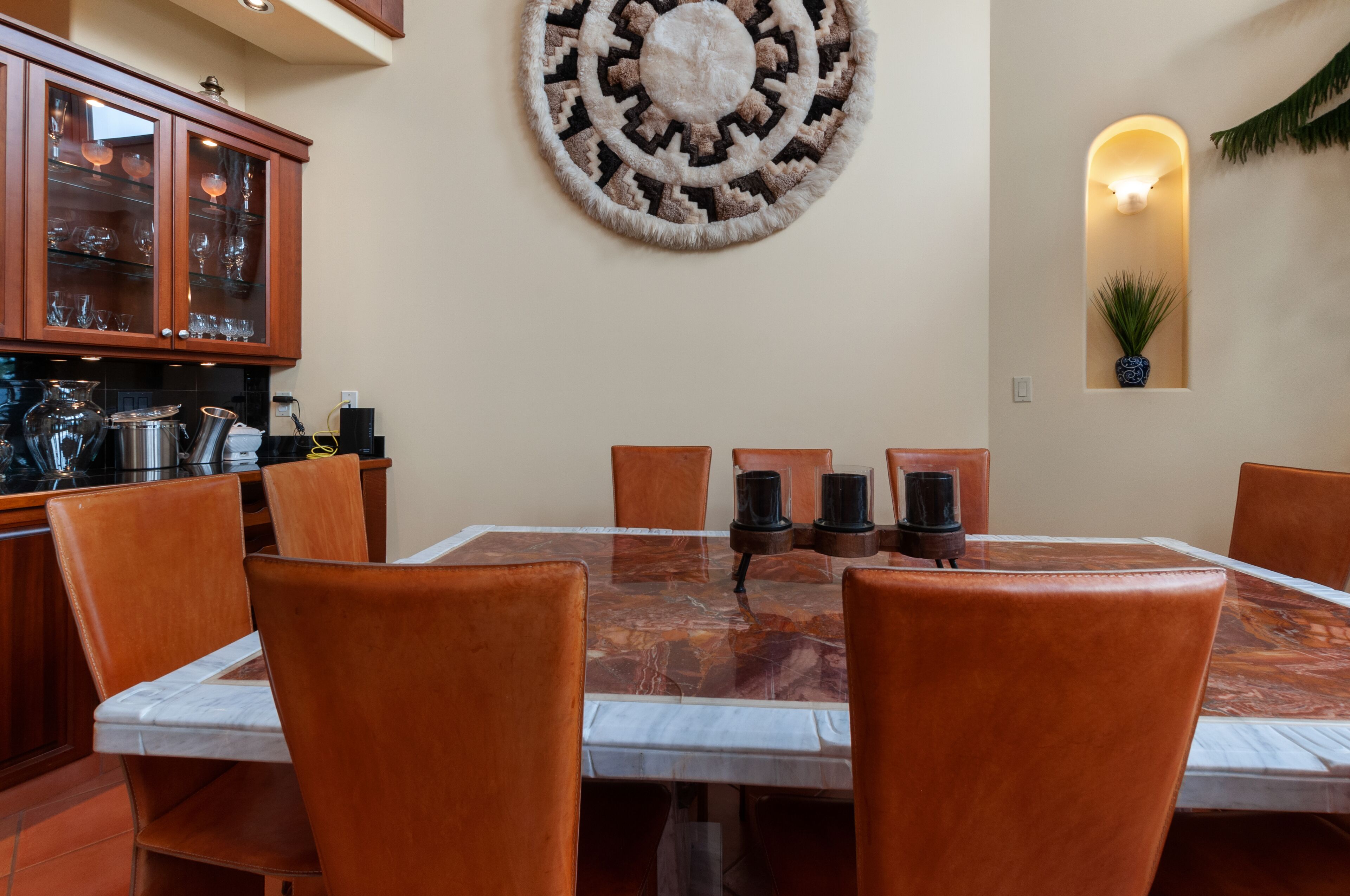 Un comedor con una mesa de mármol, sillas de cuero y un tapete decorativo.