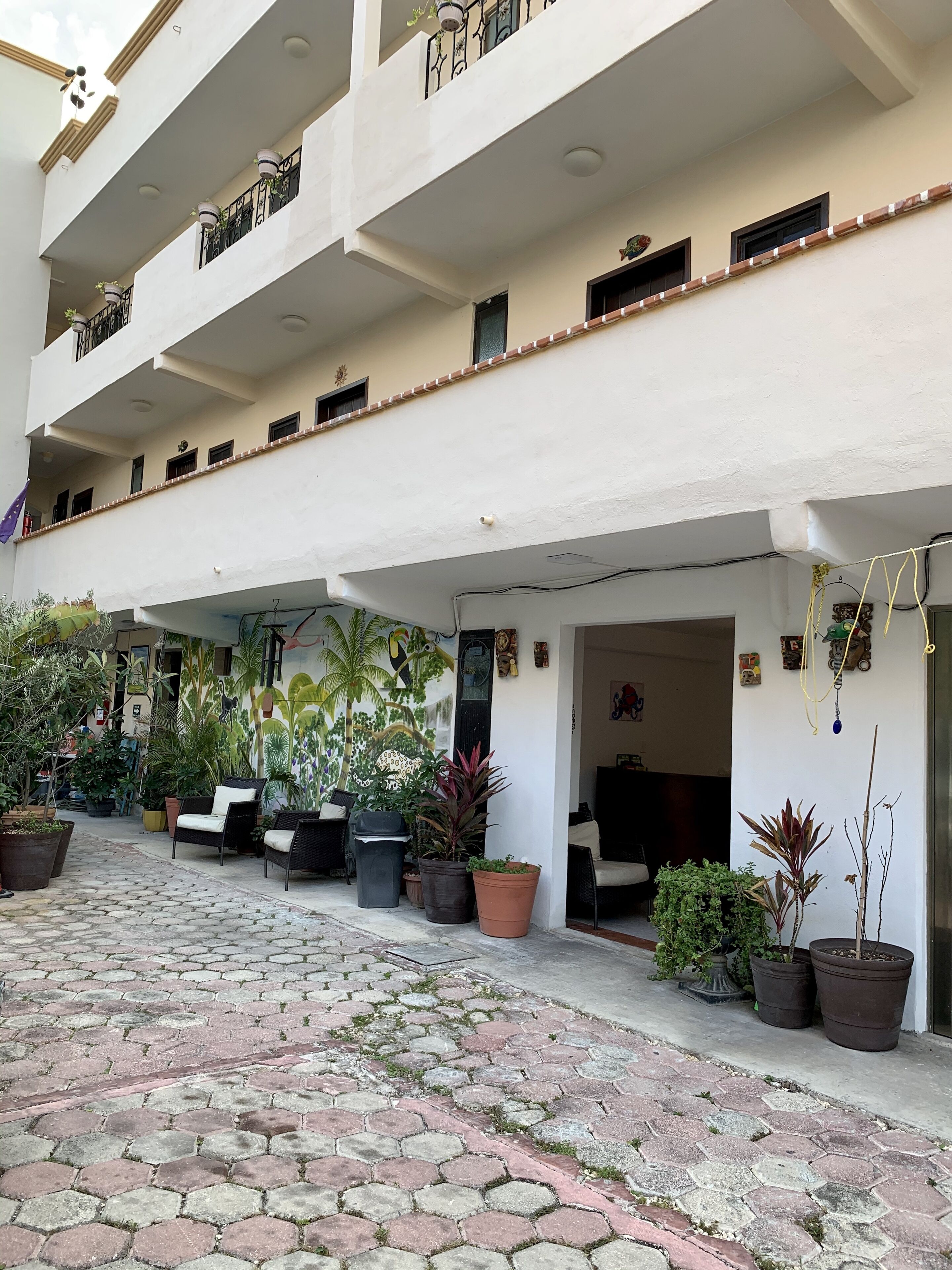 A multi-level building with a covered outdoor area featuring potted plants and seating.