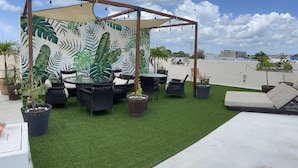 A rooftop terrace with artificial grass, wicker furniture, and a mural of tropical leaves. - Suites Fenicia (Playa del Carmen)