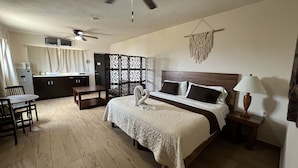 A hotel room with a bed, a desk, a chair, a wardrobe, and a kitchenette. - Suites Fenicia (Playa del Carmen)
