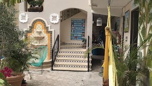 A courtyard with a staircase leading to a building entrance, surrounded by potted plants and a decorative wall with a welcome sign. - Suites Fenicia (Playa del Carmen)