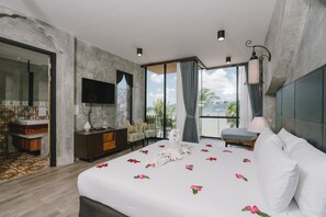 Ein modernes Hotelzimmer mit einem großen Bett, einem Flachbildfernseher, einem Balkon mit Blick und einer Wand mit Steinoptik.