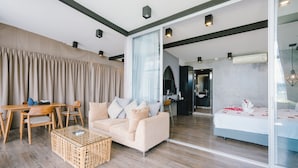 A modern living room with a sofa, coffee table, and curtains. - Patong Signature Boutique Hotel (Patong)