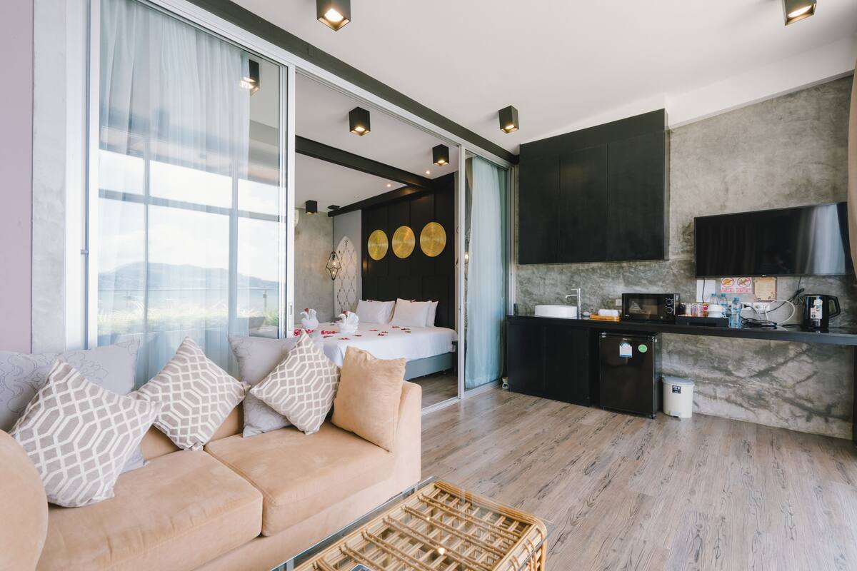 Ein modernes Wohnzimmer mit einer Couch, einem Korbwäschesessel und einem Bett mit Blick auf die Stadt.