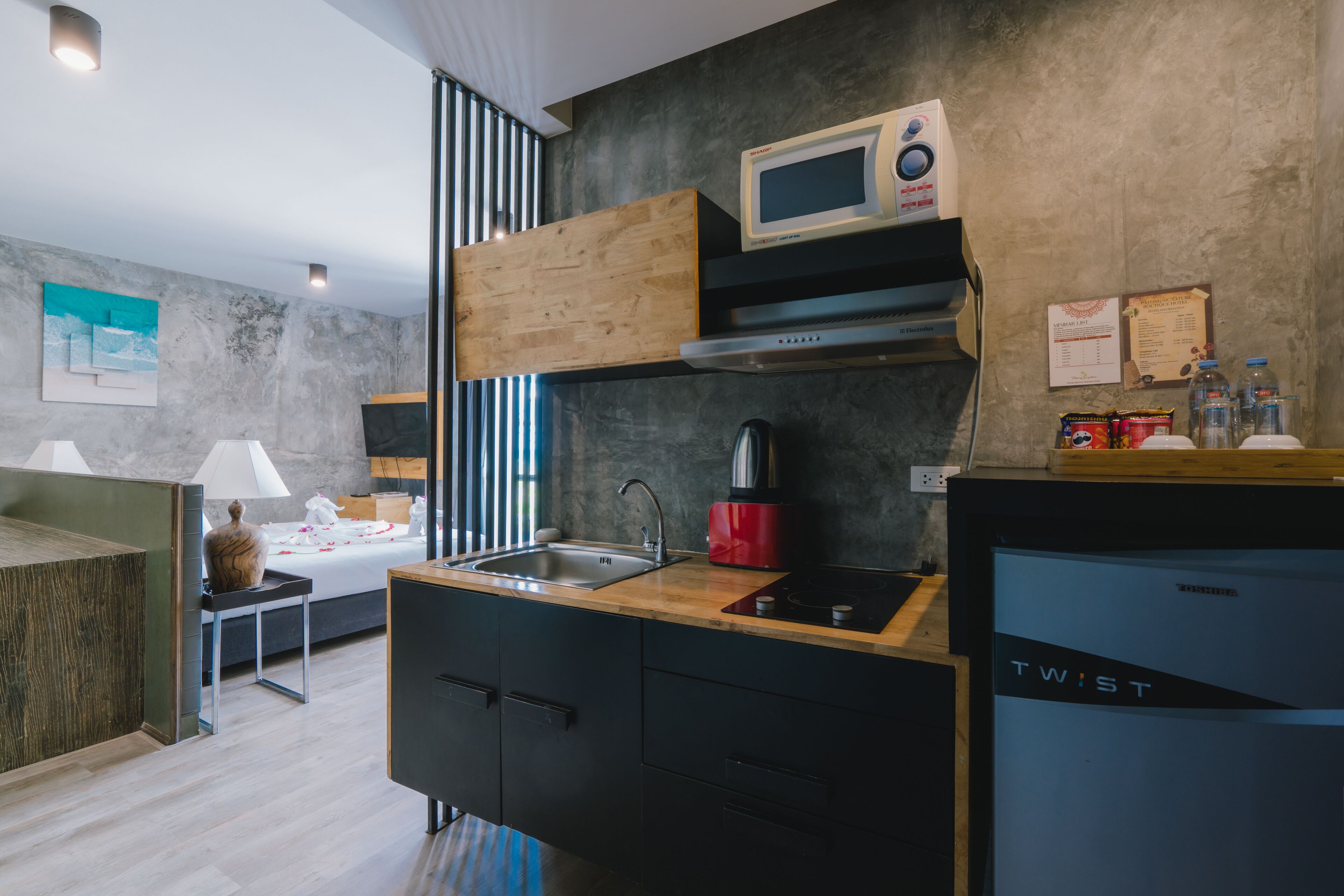 Una cocina moderna con microondas incorporado, cafetera roja y un refrigerador compacto.