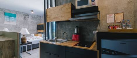 Una cocina moderna con microondas incorporado, cafetera roja y un refrigerador compacto.