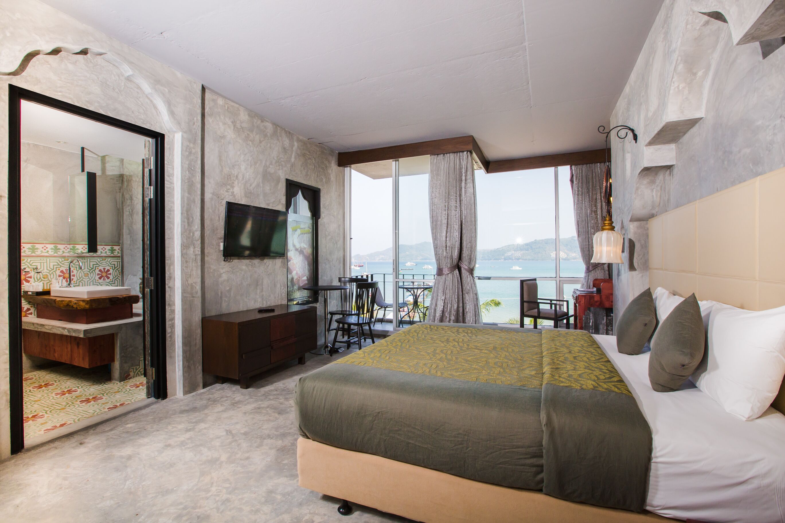 Une chambre avec un grand lit, une télévision, un bureau et une vue sur la mer.