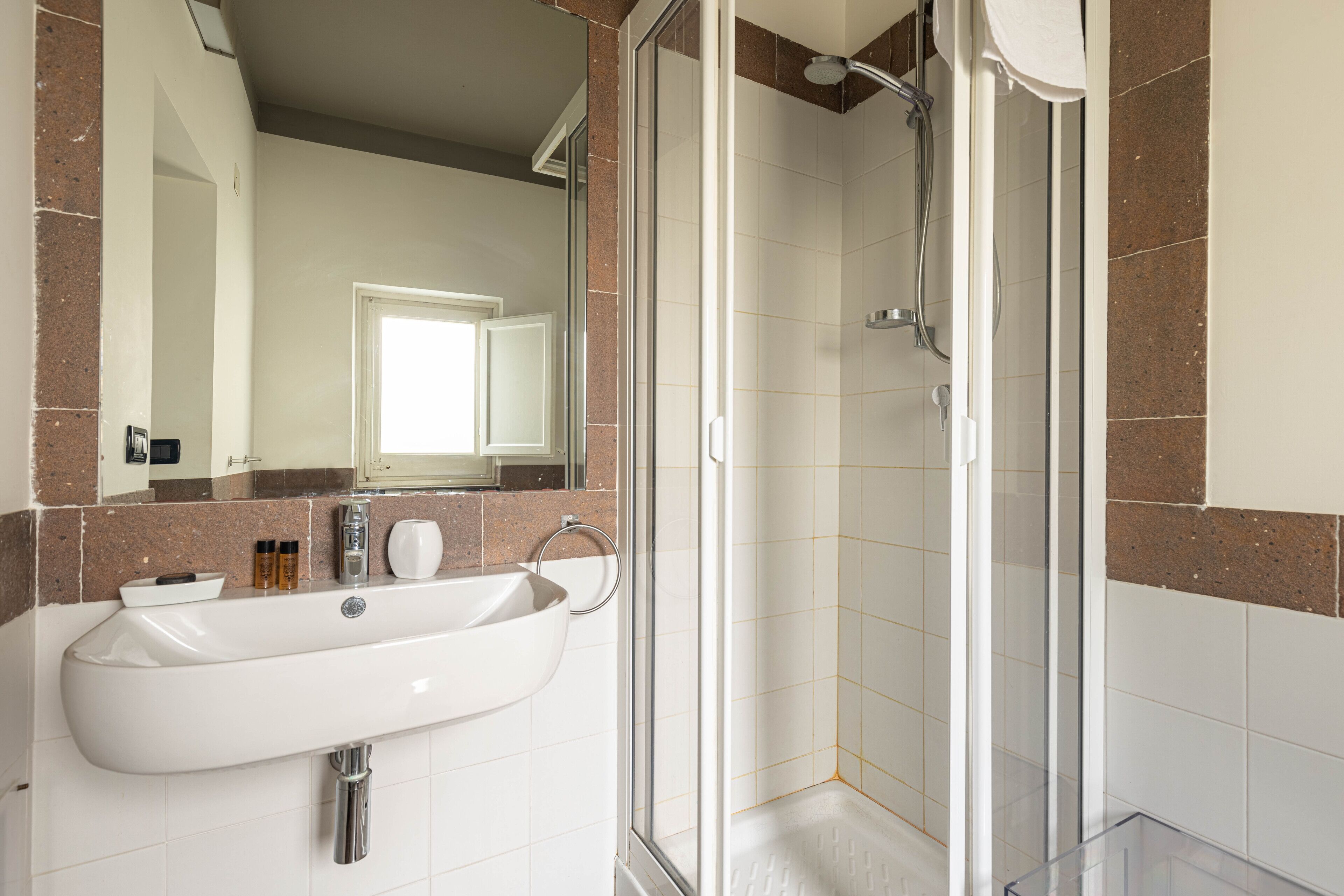 A bathroom with a white sink, a glass shower enclosure, and a mirror above the sink.