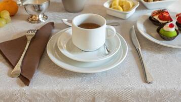 A breakfast table with a cup of coffee, plates of food, and a small cactus plant.