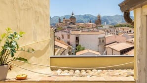 Vista desde un balcón sobre un pueblo histórico con edificios y montañas al fondo.