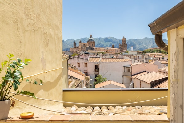 Vista desde un balcón sobre un pueblo histórico con edificios y montañas al fondo.