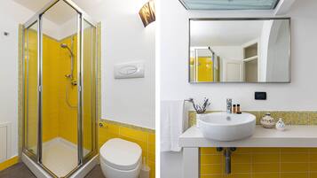 A bathroom with a glass shower enclosure, a white toilet, and a sink with a mirror above it.