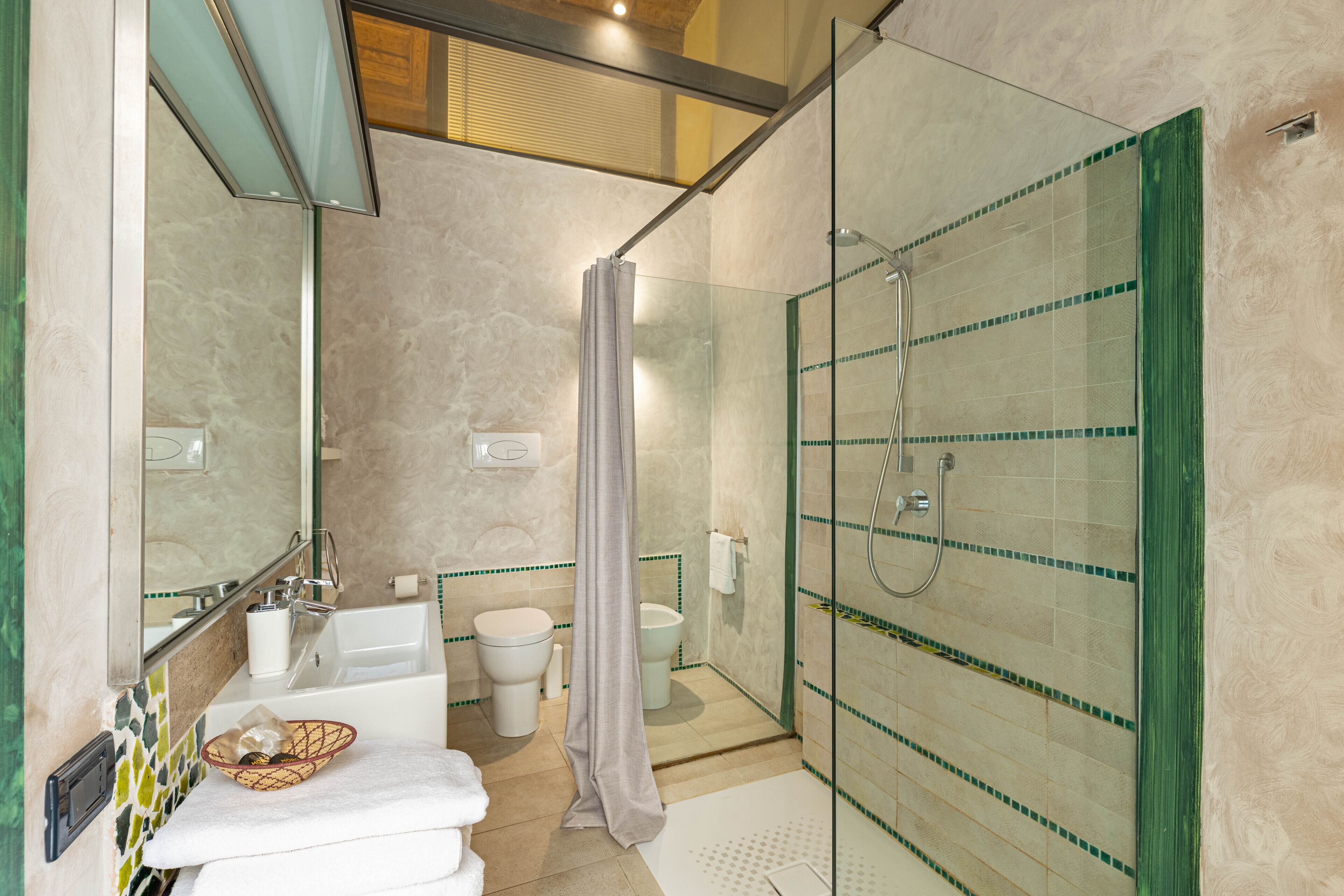 A bathroom with a glass-enclosed shower, a bathtub, and a toilet.