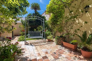 A courtyard with a metal gate, potted plants, and a tiled floor.