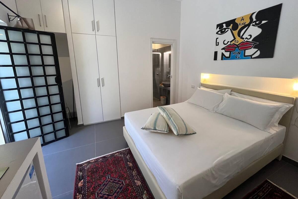 A bedroom with a bed, a wardrobe, and a bathroom visible through an open door.