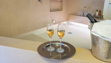 Ein Badezimmer mit einer Badewanne, zwei Champagnergläser auf einem Tablett und einem großen Champagnerflaschen-Behälter.