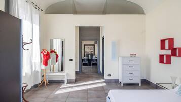 Una habitación de hotel con cama, cómoda, tocador con espejo, una silla y escritorio con sillas.