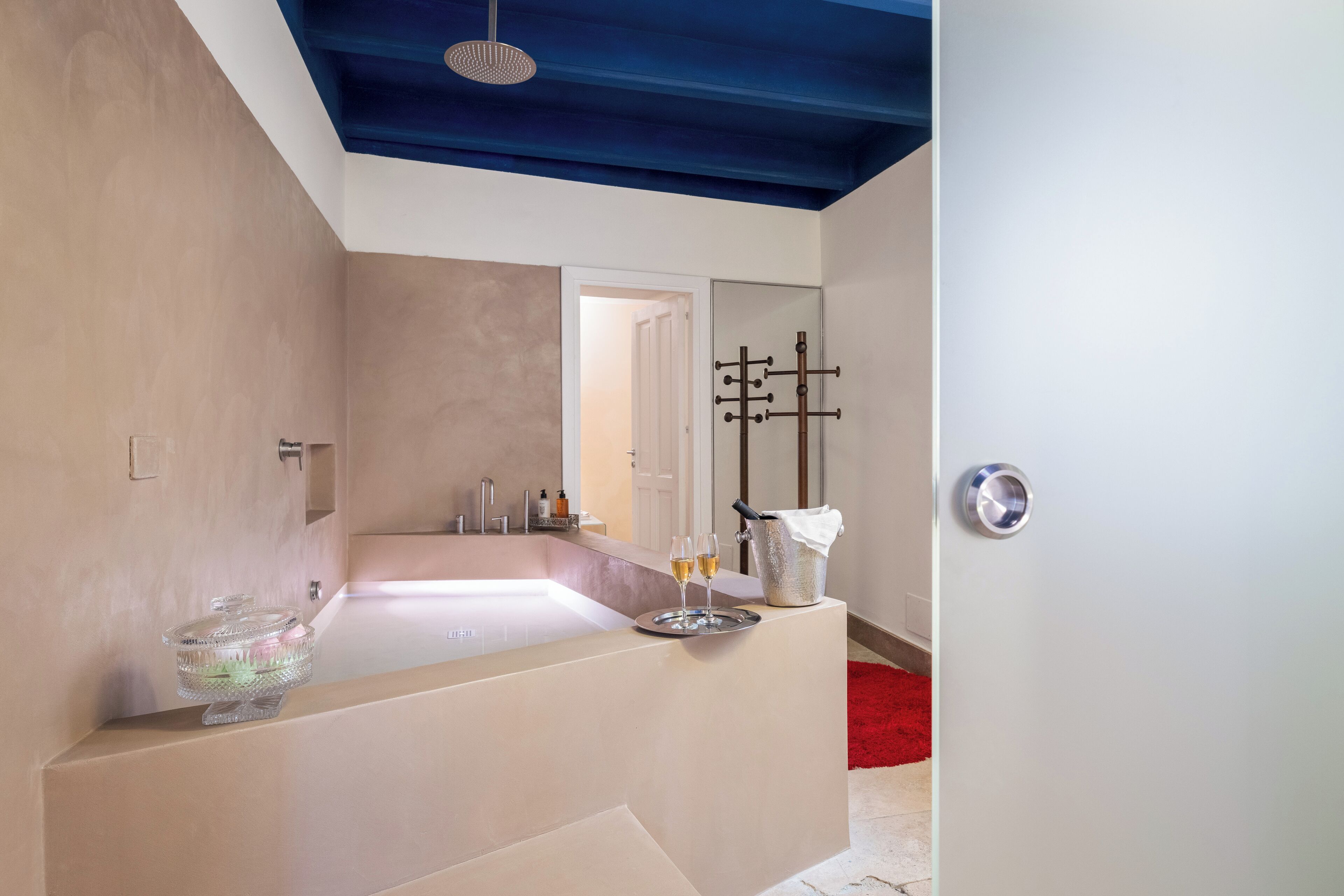 A modern bathroom with a large bathtub, a glass container, and a metal bucket.