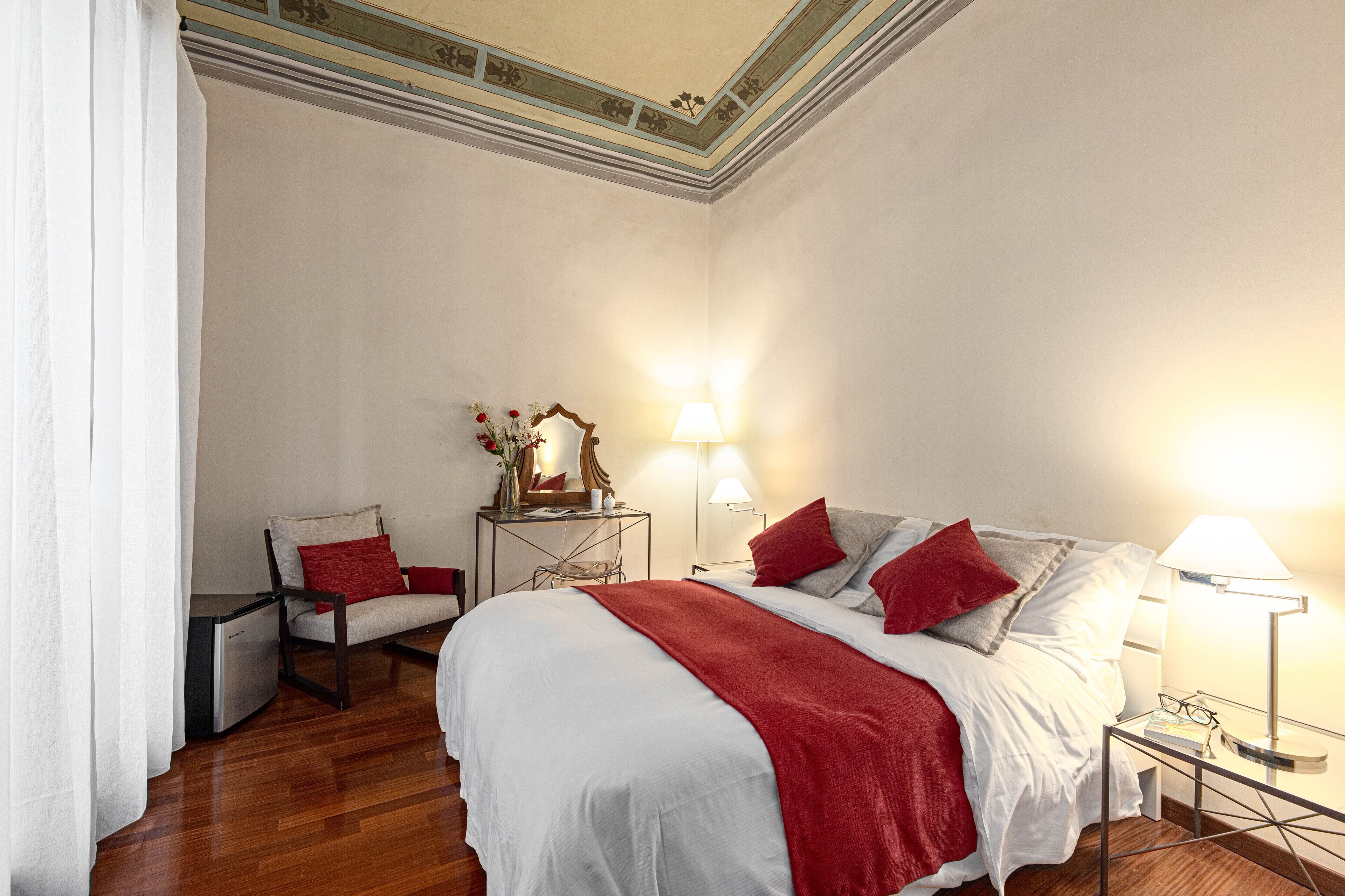 Een hotelkamer met een bed, een stoel, een tafel en twee lampen.