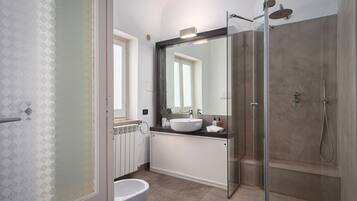 Une salle de bain moderne avec une douche à parois de verre, un lavabo blanc et un grand miroir.