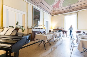 Una sala elegante con un pianoforte, tavoli, sedie e un camino.