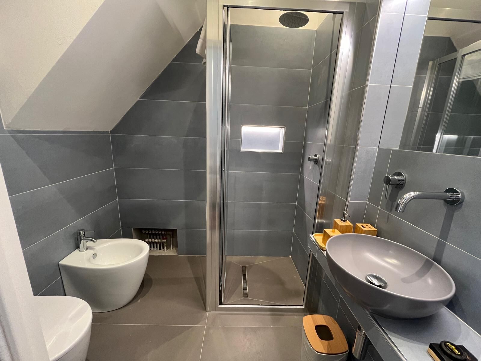 Un baño moderno con ducha a nivel, un bidé, un lavamanos grande y un inodoro.