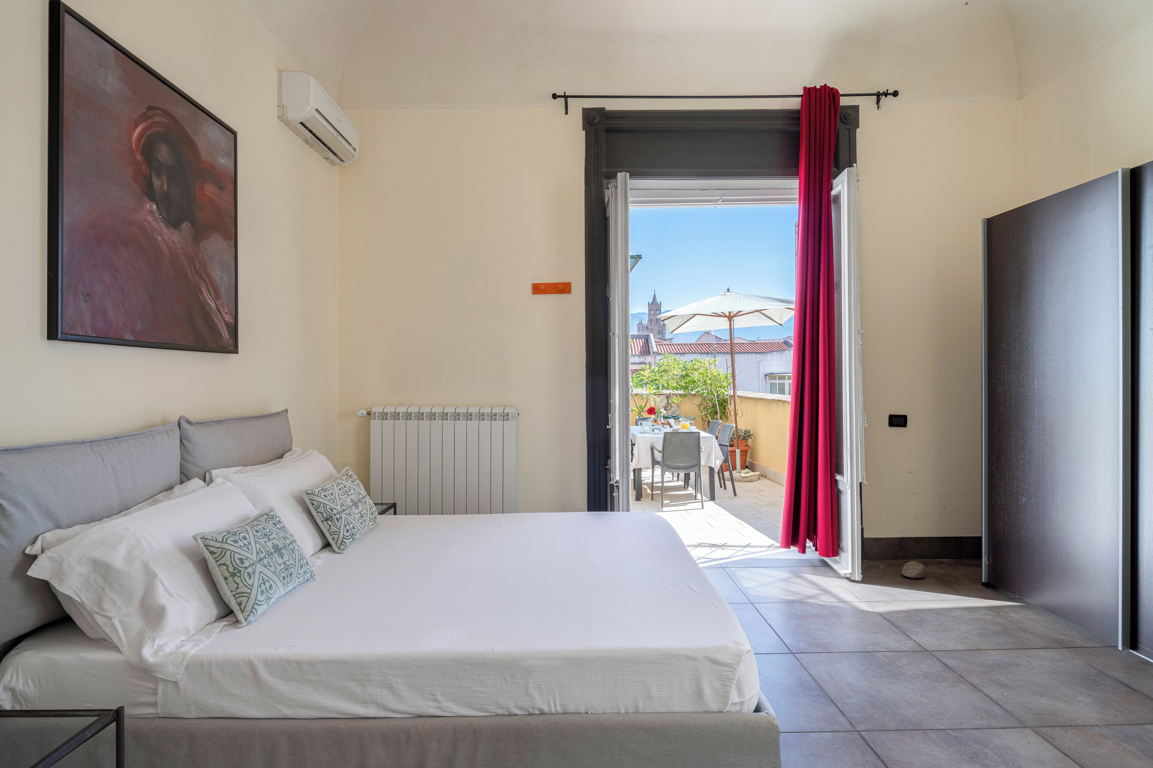 Un dormitorio con una cama, un radiador y vistas a un patio exterior.