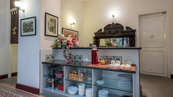 A reception area with a counter displaying plates, bowls, and a vase of flowers. There are framed pictures on the wall, a mirror above the counter, and a 'STAFF ONLY' door to the right.