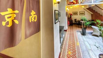 A hallway with a patterned floor, a hanging lantern, and a wall with a floral painting.
