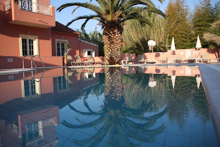 Una piscina al aire libre, sombrillas, sillones reclinables de piscina