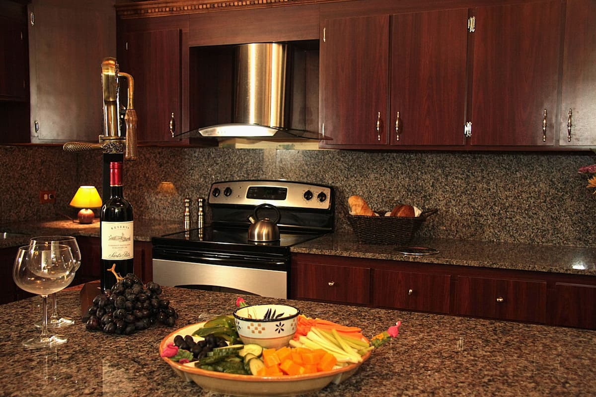 A kitchen with granite countertops, a stainless steel range hood, and wooden cabinets.