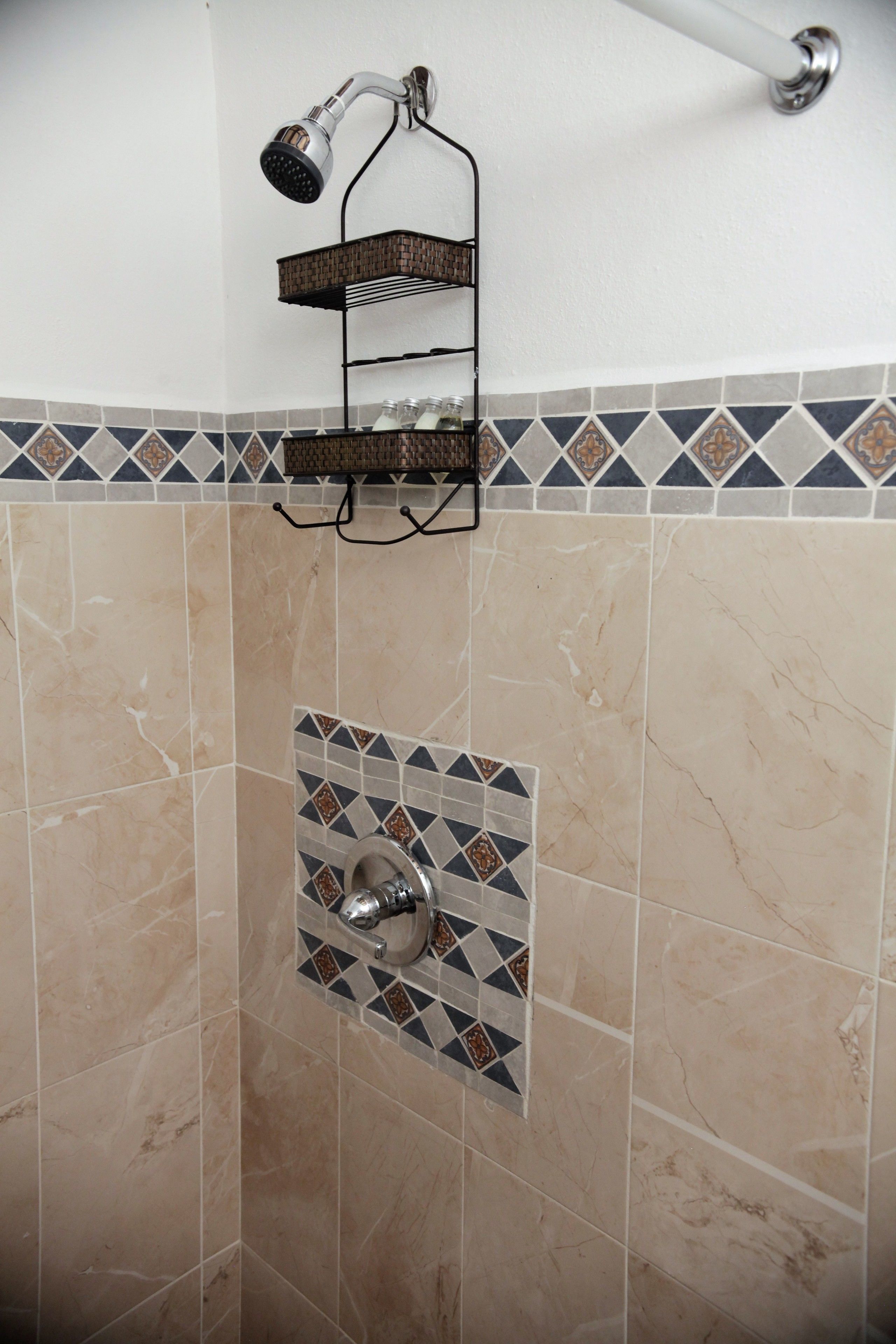 Un espace douche doté d’une étagère fixée au mur et d’un pommeau de douche.