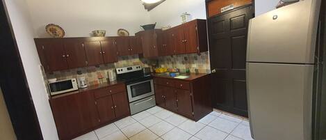 A kitchen with wooden cabinets, a stainless steel refrigerator, a microwave, and a stove.
