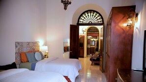 A hotel room with two beds, a wooden cabinet, a TV, and a hallway leading to a dining area. - Fortaleza Suites (San Juan)