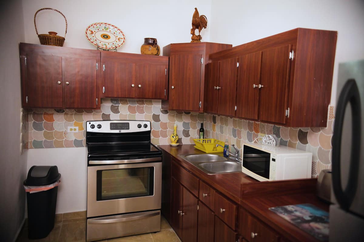 A kitchen with wooden cabinets, a stainless steel oven, a microwave, and a sink.