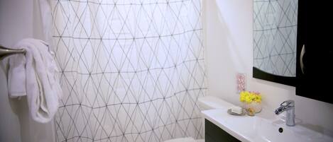 A bathroom with a white toilet, a sink with a mirror, and a shower curtain with a geometric pattern.