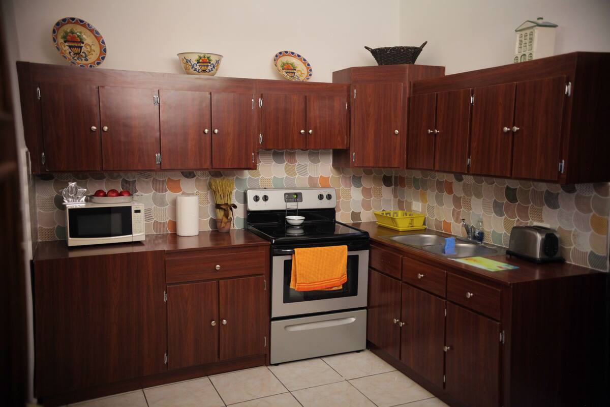 A kitchen with wooden cabinets, a microwave, an oven, and a sink.