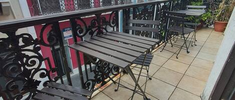 A balcony with metal railings and wooden tables.
